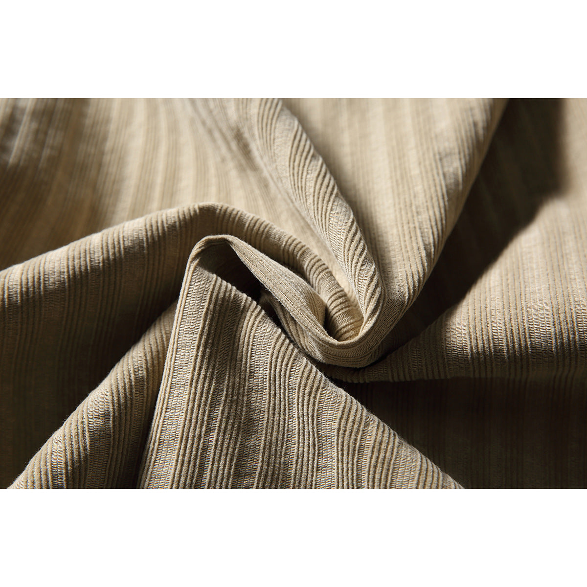 Close-up of beige fabric with fine, irregular vertical stripes, folded to show its texture.