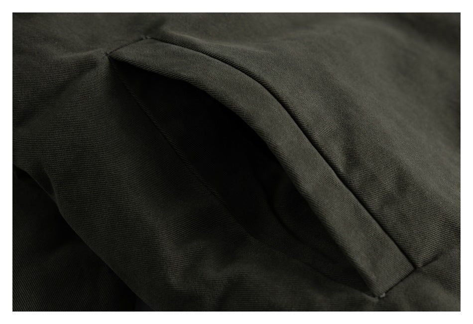 Close-up of a curved pocket opening and stitching on olive-gray jacket fabric.