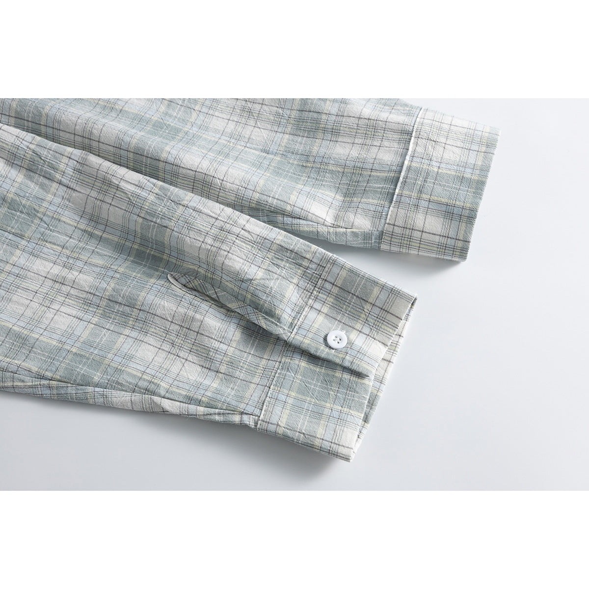 Close-up of a pale blue-gray plaid sleeve cuff with a button and buttonhole.