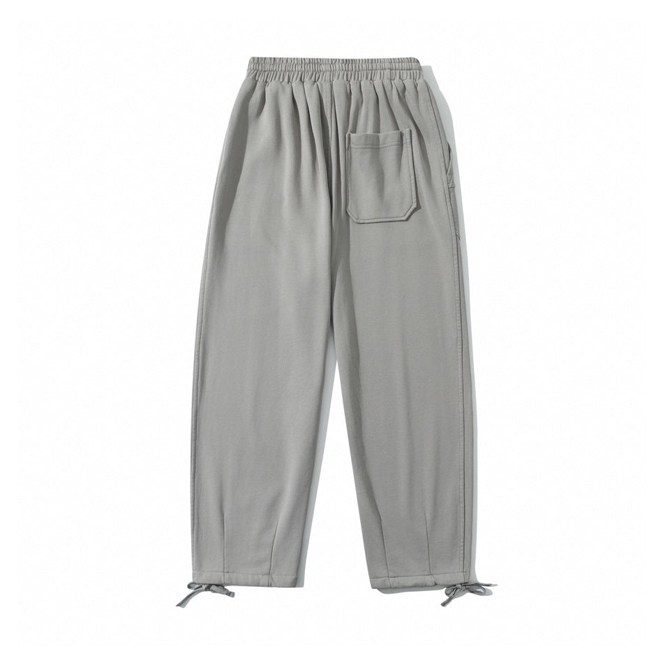 Back view of light gray pants with an elastic waistband, one rear pocket, and tie cuffs.