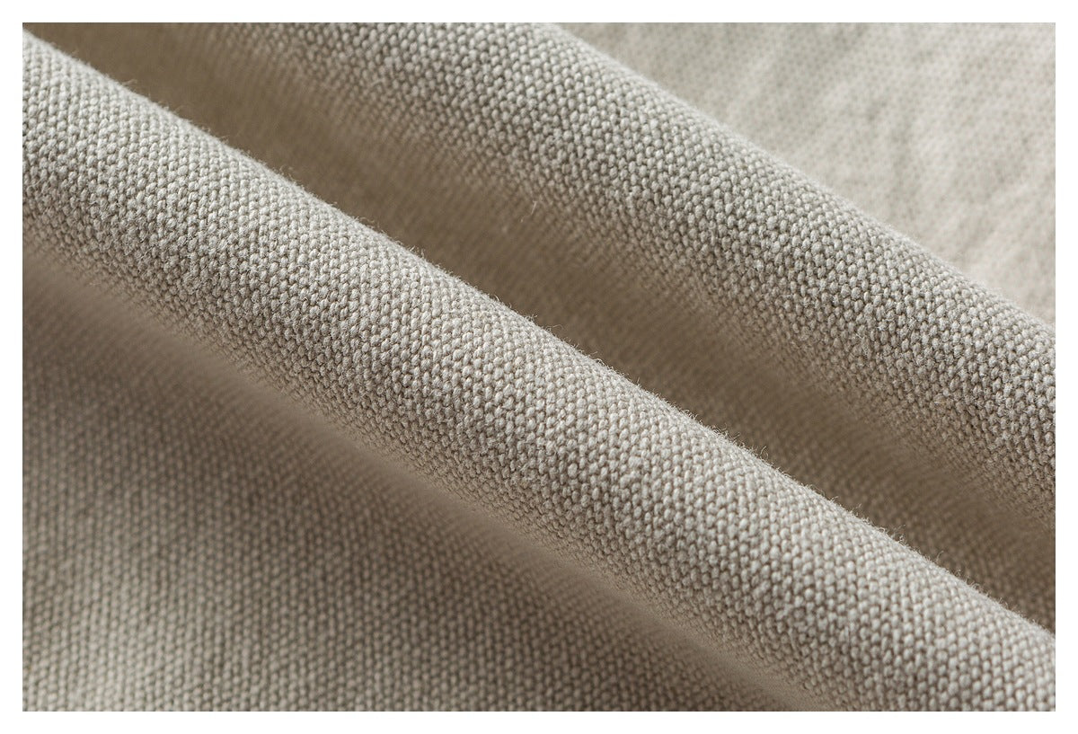 Macro view of the textured weave in light beige fabric folded into soft ridges.
