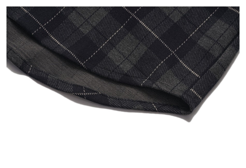 Close-up of the charcoal plaid shirt's curved hem and stitched edge.