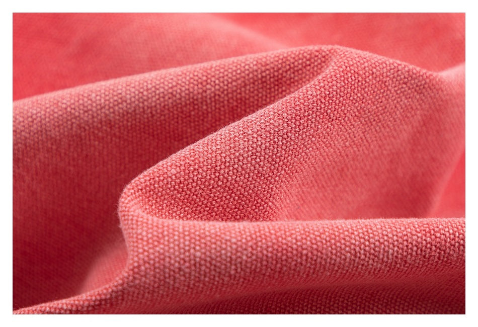 Macro view of coral-red woven fabric draped in soft folds, showing its textured surface.