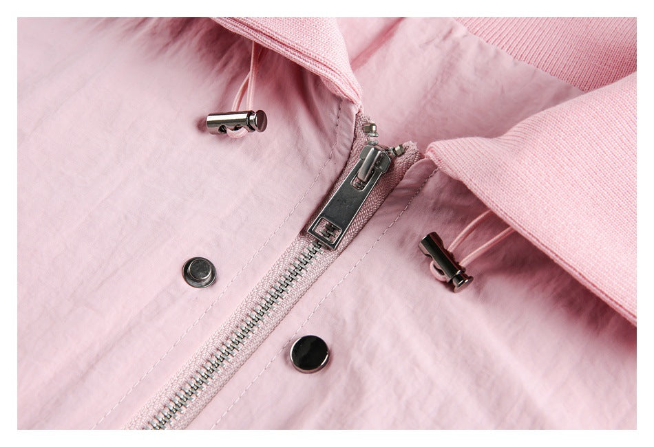 Close-up of a pale pink jacket front with a metal zipper, snap buttons, and drawcord toggles.