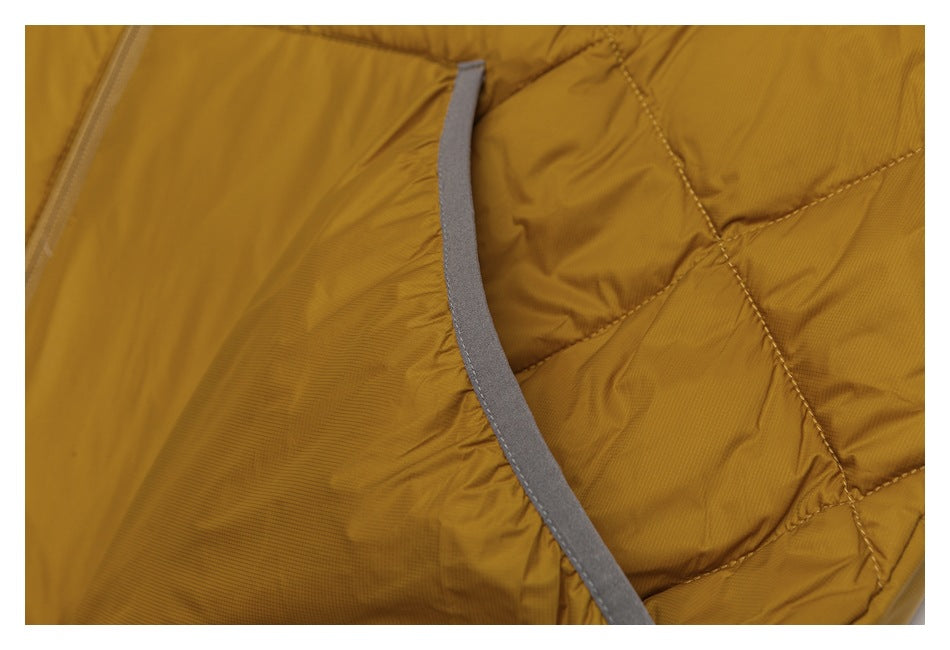 Close-up of mustard-gold quilted jacket fabric with a curved gray binding strip and visible seam stitching.