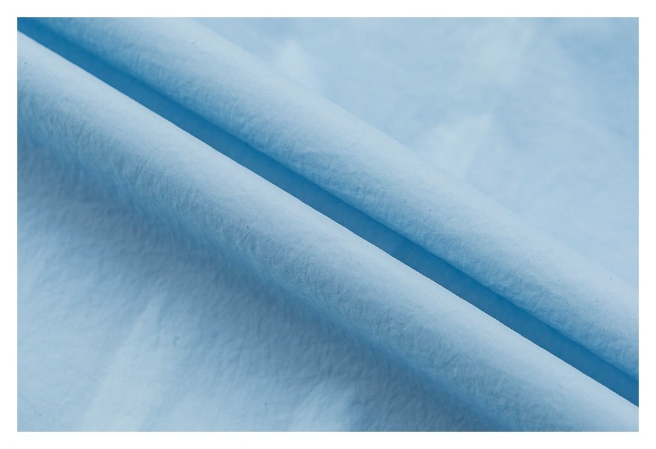 Close-up of pale blue fabric folded diagonally to show its surface and layered edge.