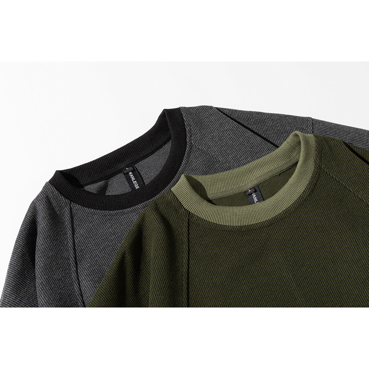 Close-up of charcoal gray and olive crewneck sweatshirts with ribbed collars and fine diagonal texture.