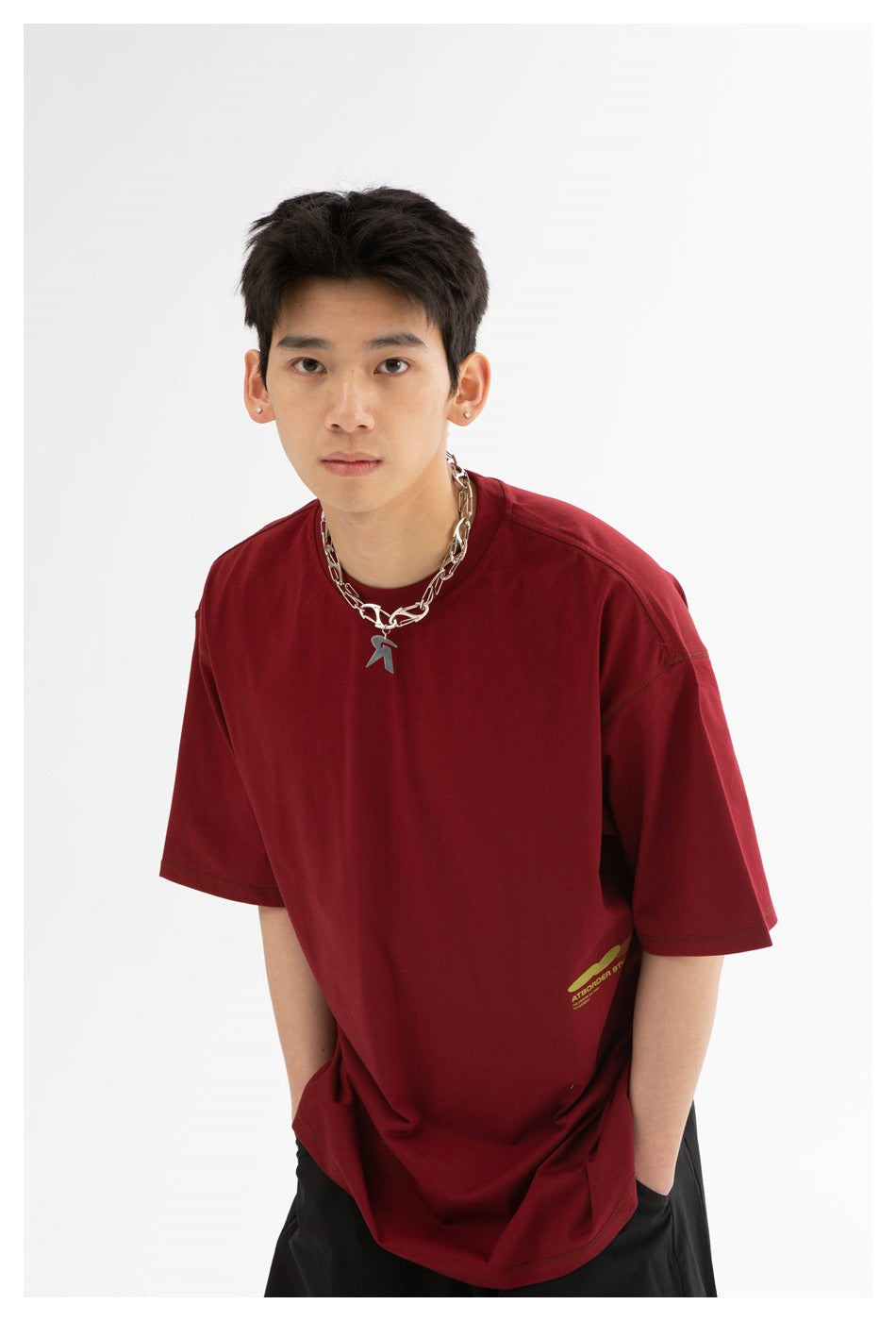 Front view of a model wearing an oversized burgundy T-shirt with a small yellow-green graphic near the hem.