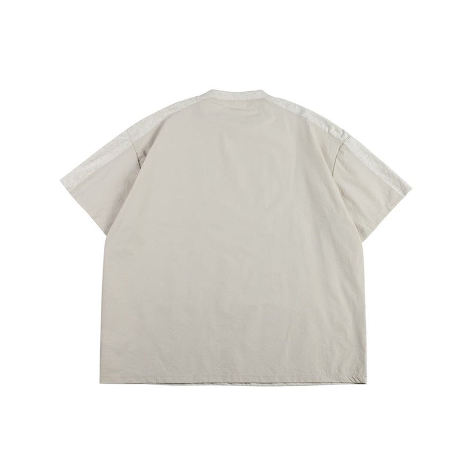 Back of a pale beige short-sleeve T-shirt with heathered gray shoulder yoke panels, flat lay
