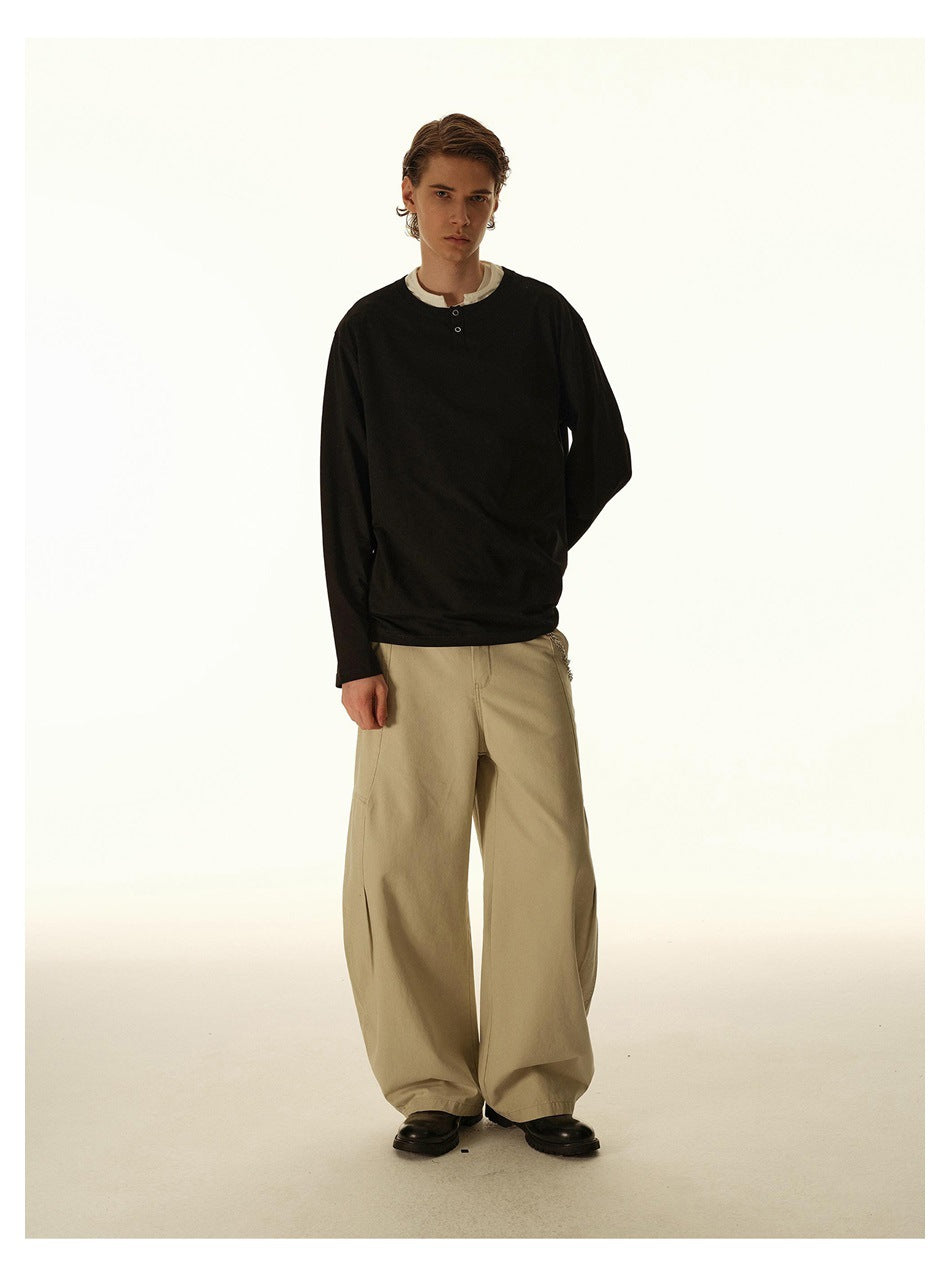 Full-length view of a model in a black long-sleeve henley and loose beige trousers.