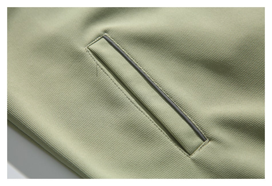 Close-up of a narrow welt pocket with dark edging on pale sage jacket fabric.