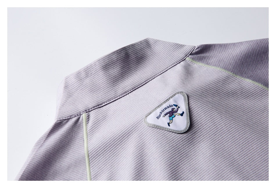 Close-up of a triangular embroidered character patch on a pale lavender-gray garment.