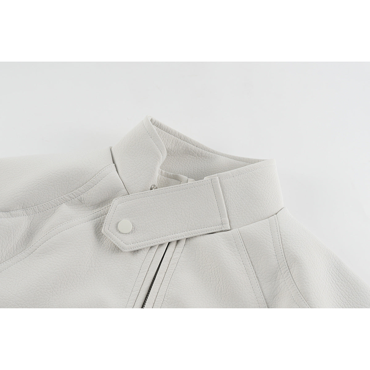 Close-up of an off-white jacket collar, snap-tab closure, stitching and front zipper.