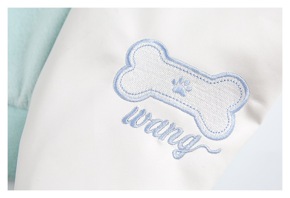Close-up of white garment with blue embroidered bone, paw print and lettering.