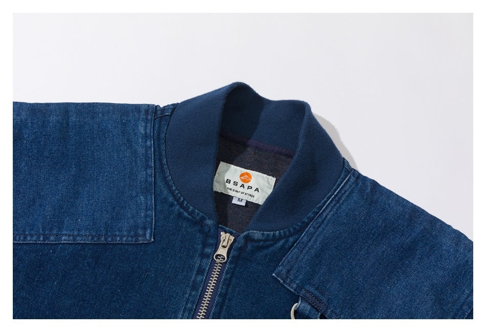 Close-up of a blue denim jacket collar, front zipper, shoulder panels, and sewn neck label.