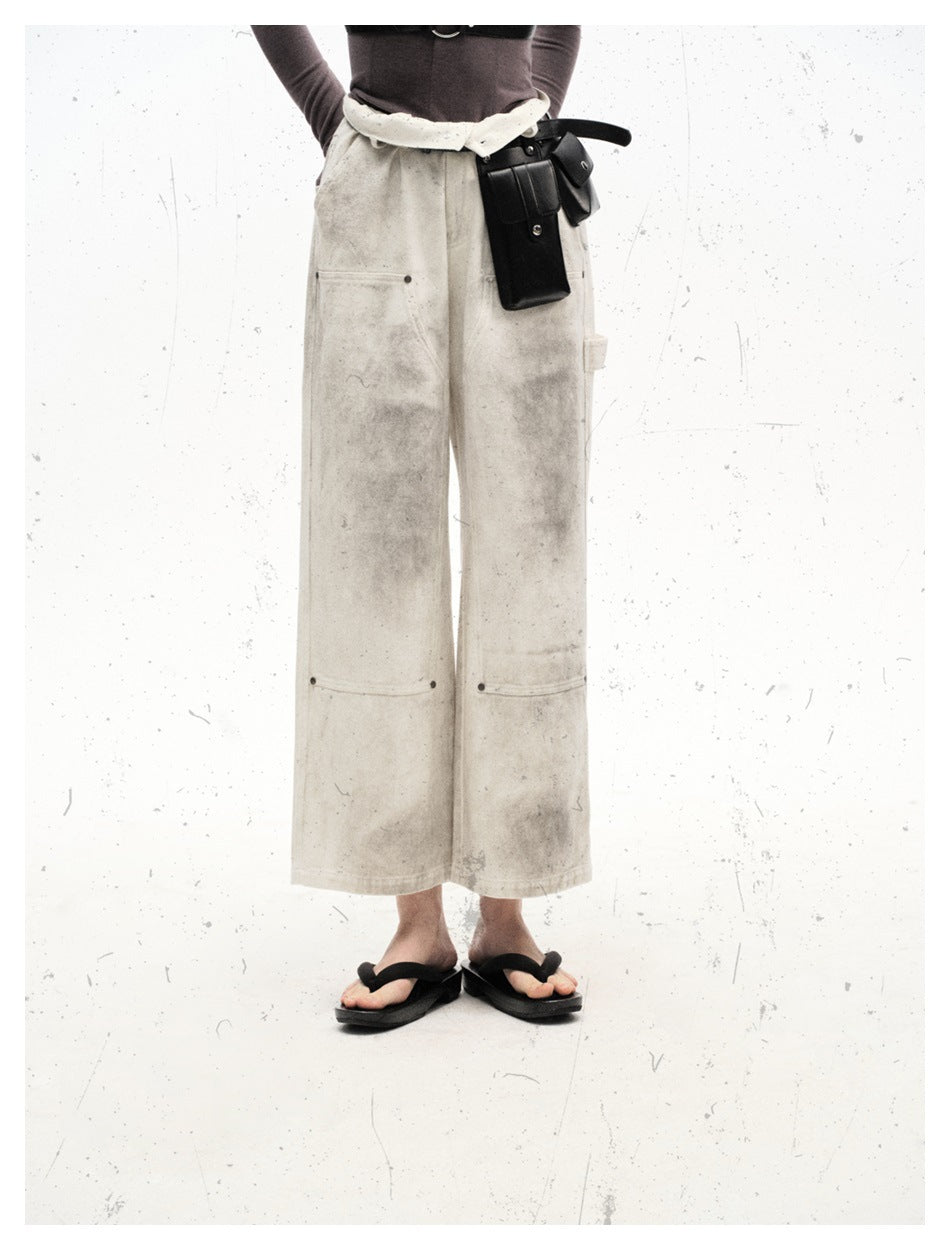 Front view of a model wearing off-white wide-leg trousers with gray distressed marks and large panel pockets.
