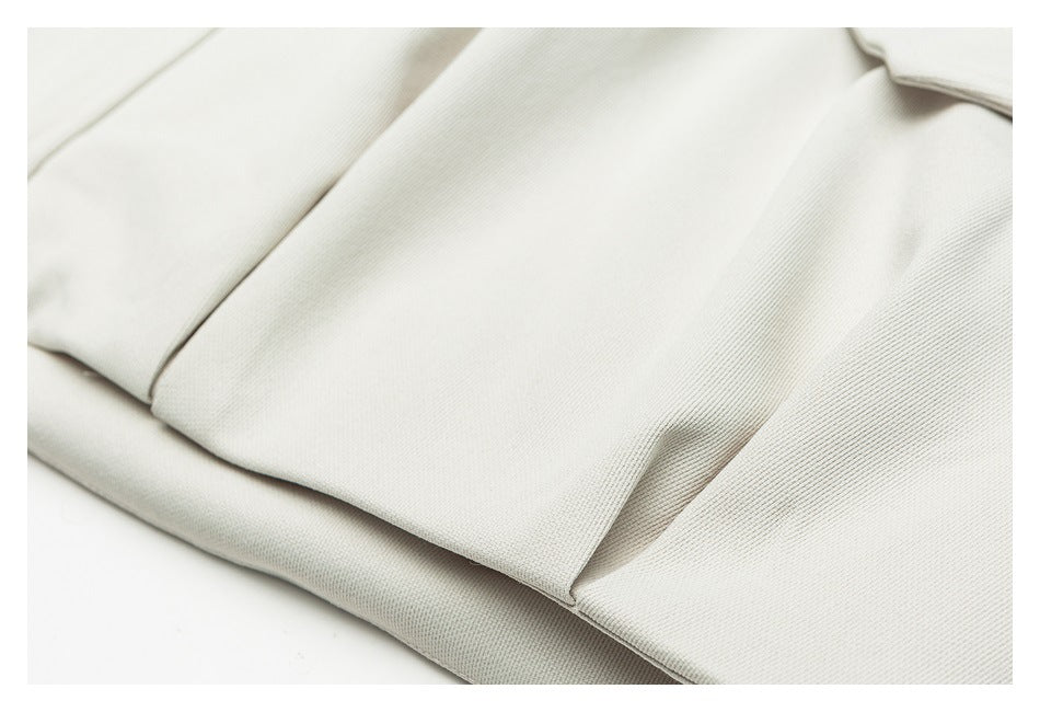 Close-up of an off-white jacket's folded fabric panels, seams, and hem.