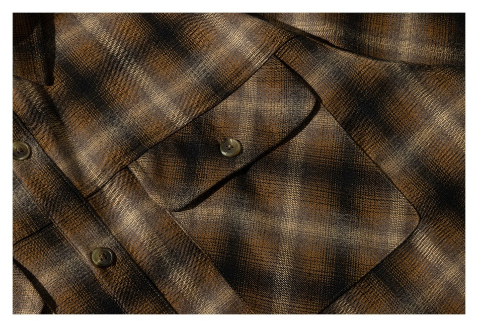 Close-up of a plaid shirt chest pocket with a buttoned flap and front placket.