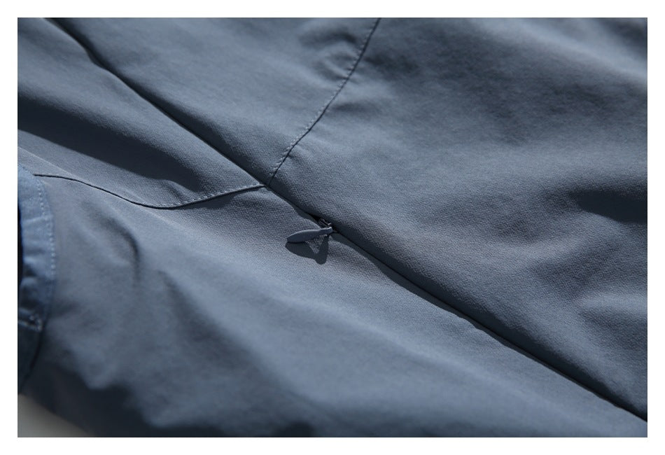 Close-up of a small fabric tab beside a diagonal seam on the slate blue-gray garment.