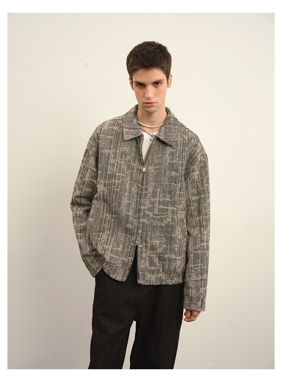 Closer view of a man wearing a gray patterned collared zip jacket over a light shirt.
