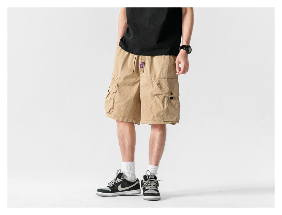 Front view of a model wearing tan cargo shorts with large flap pockets and a drawstring waist.