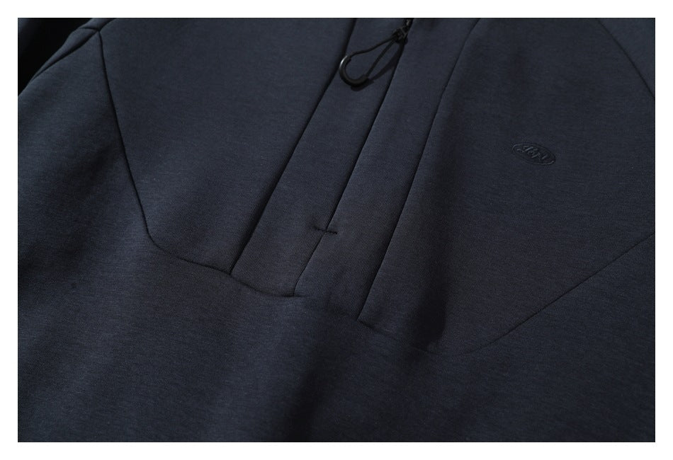 Close-up of a dark navy pullover's short zip placket and small tonal chest emblem.