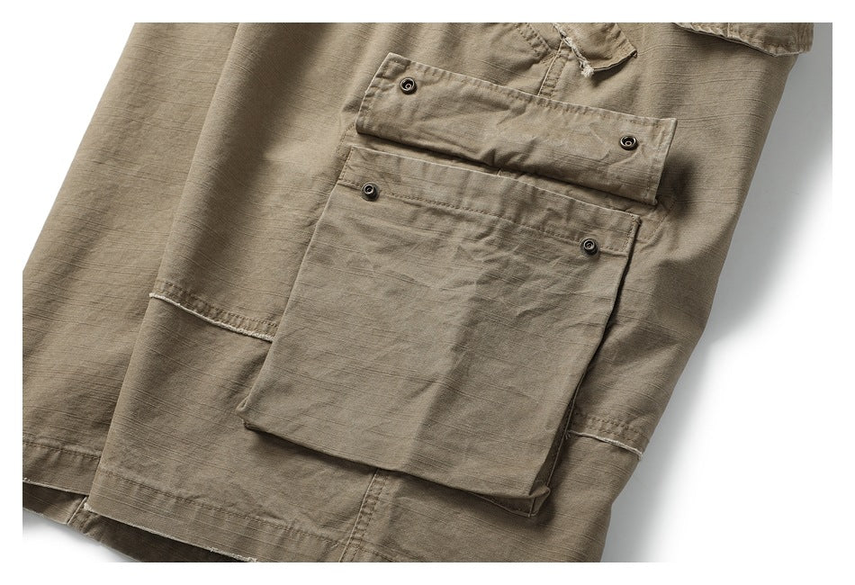 Close-up of khaki cargo trousers showing a large buttoned flap pocket and stitched panels.