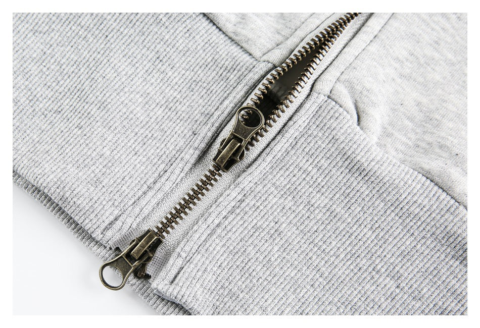 Close-up of a light gray jacket's metal zipper and ribbed knit cuff.