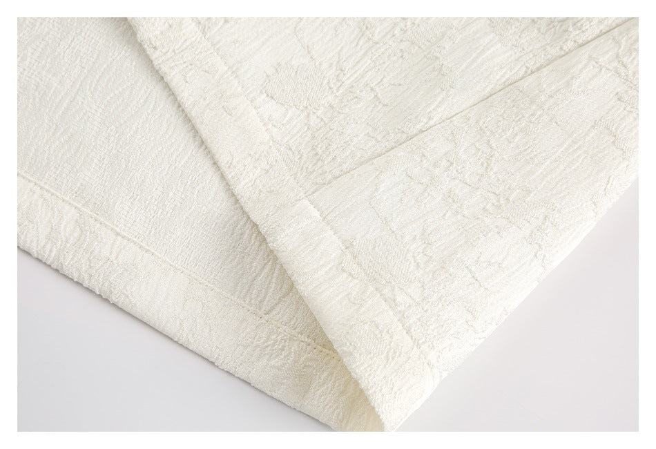 Close-up of the ivory garment's textured fabric, stitched seam, and folded edge.