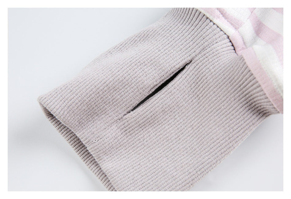 Close-up of a pale gray ribbed sleeve cuff with a narrow slit beside pink-and-white striped fabric.