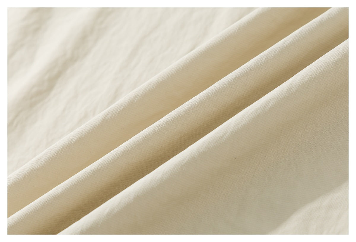 Close-up of ivory garment fabric folded to show its surface and texture.