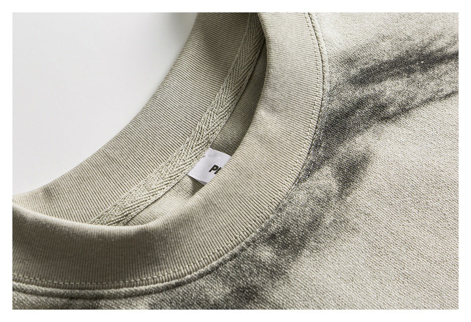 Close-up of the ribbed crew neckline and inner seam of an ivory-gray mottled shirt.
