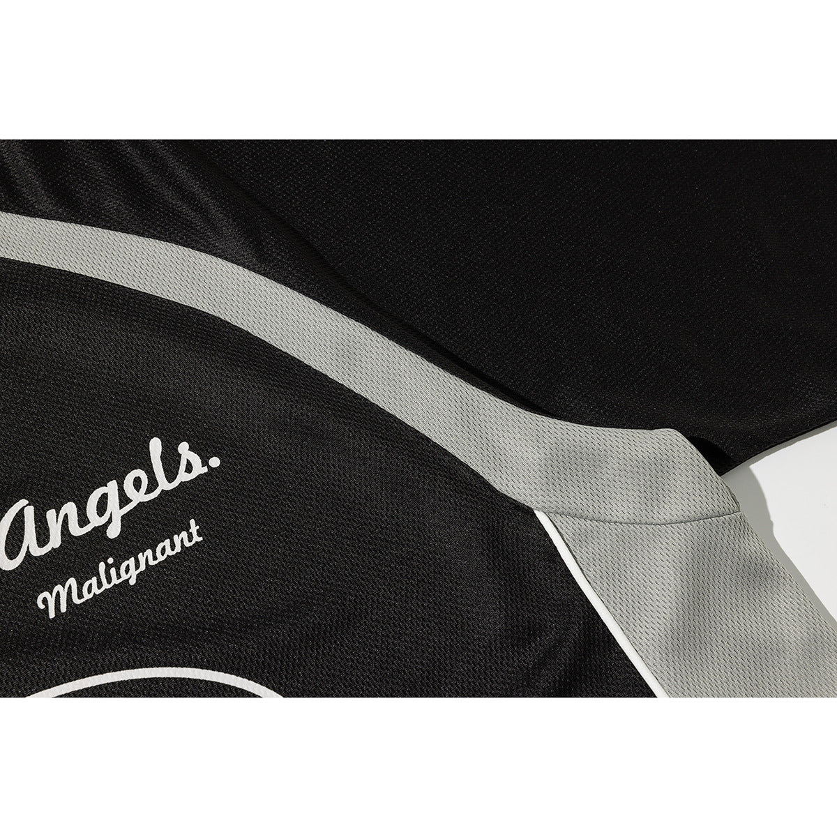 Close-up of a black jersey with a curved light gray side stripe and part of its white print.