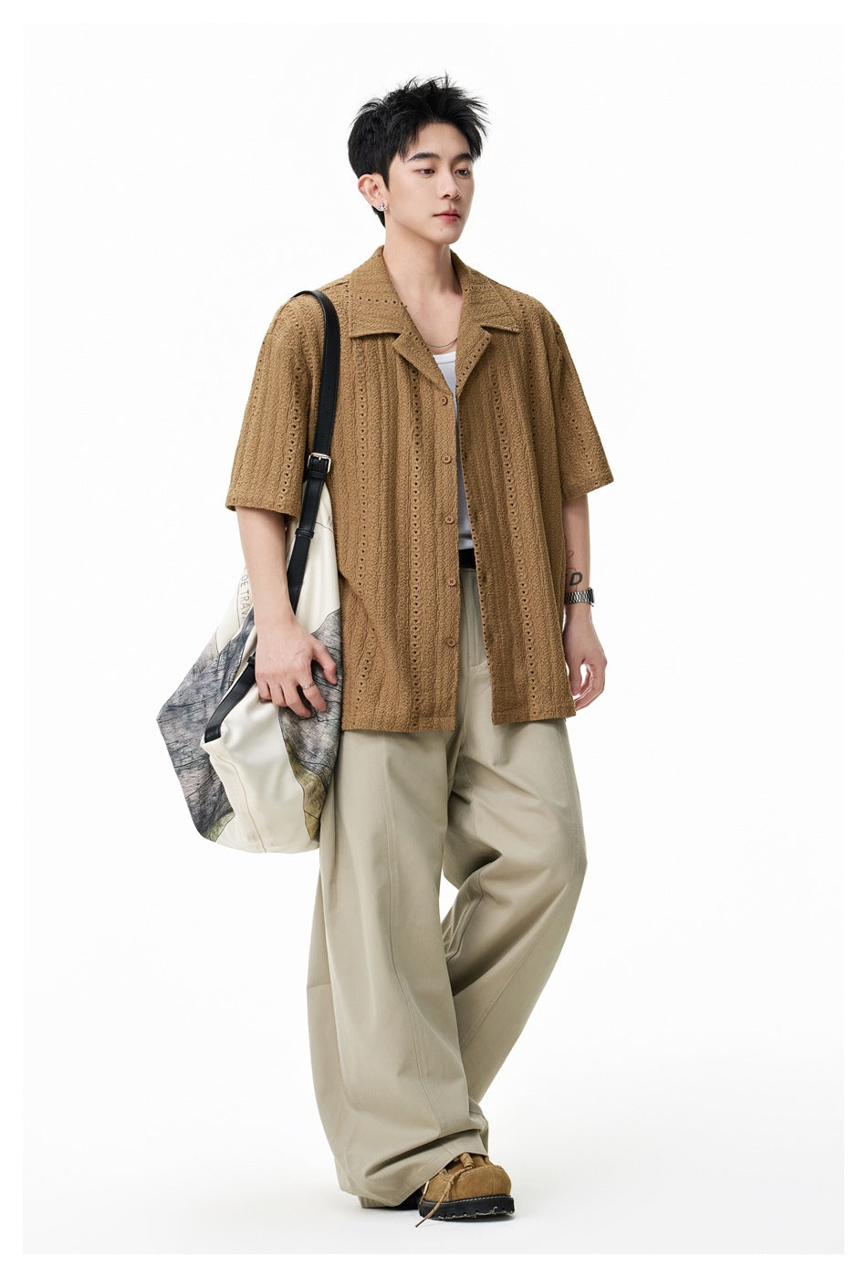 Model wearing a brown eyelet-textured short-sleeve camp-collar shirt with beige wide-leg pants, full-length view