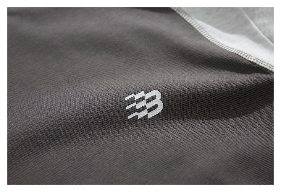 Close-up of charcoal fabric with a small white stylized logo and a curved light gray seam.