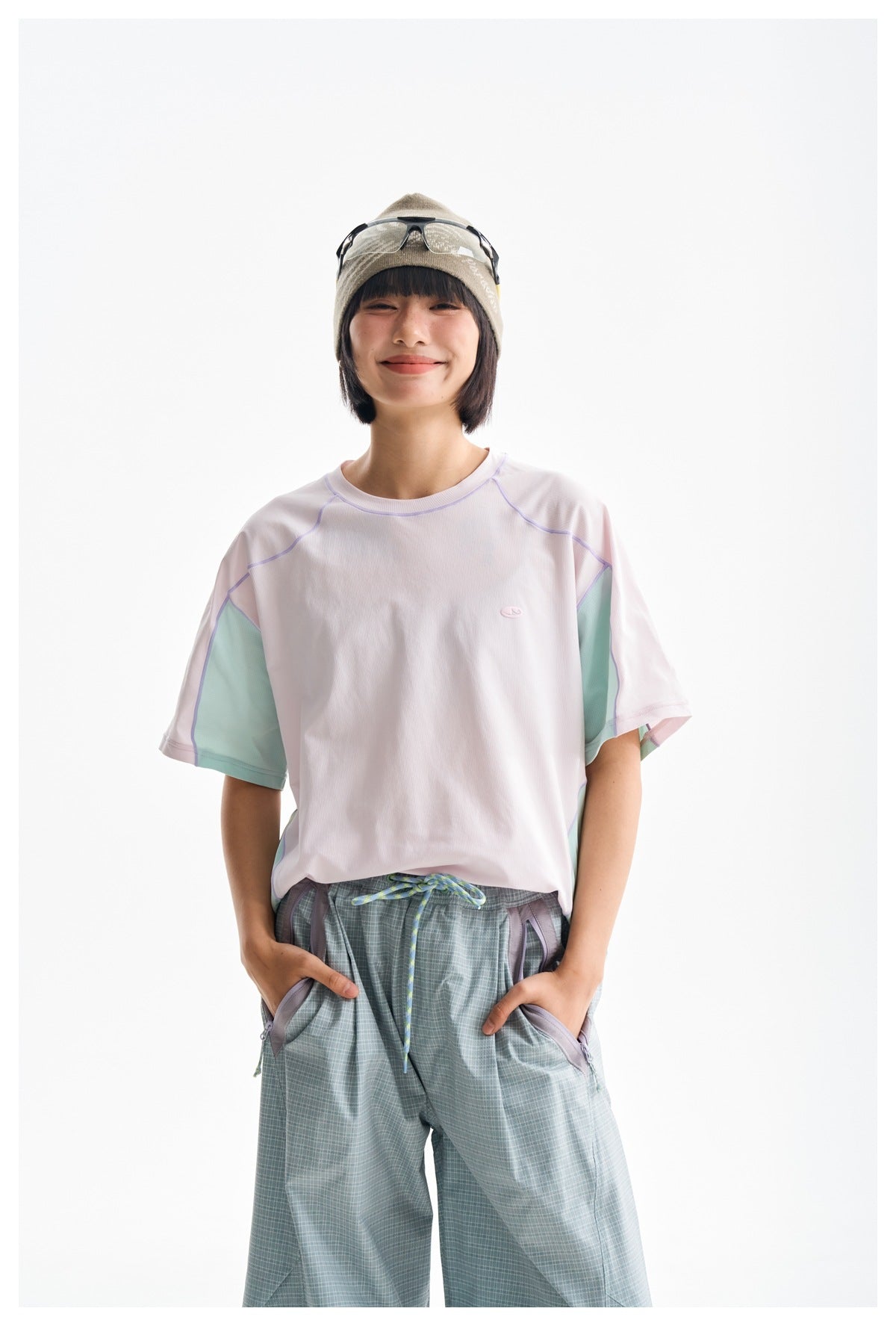 Front view of a model wearing a pale pink athletic T-shirt with mint side panels and lavender seam details.