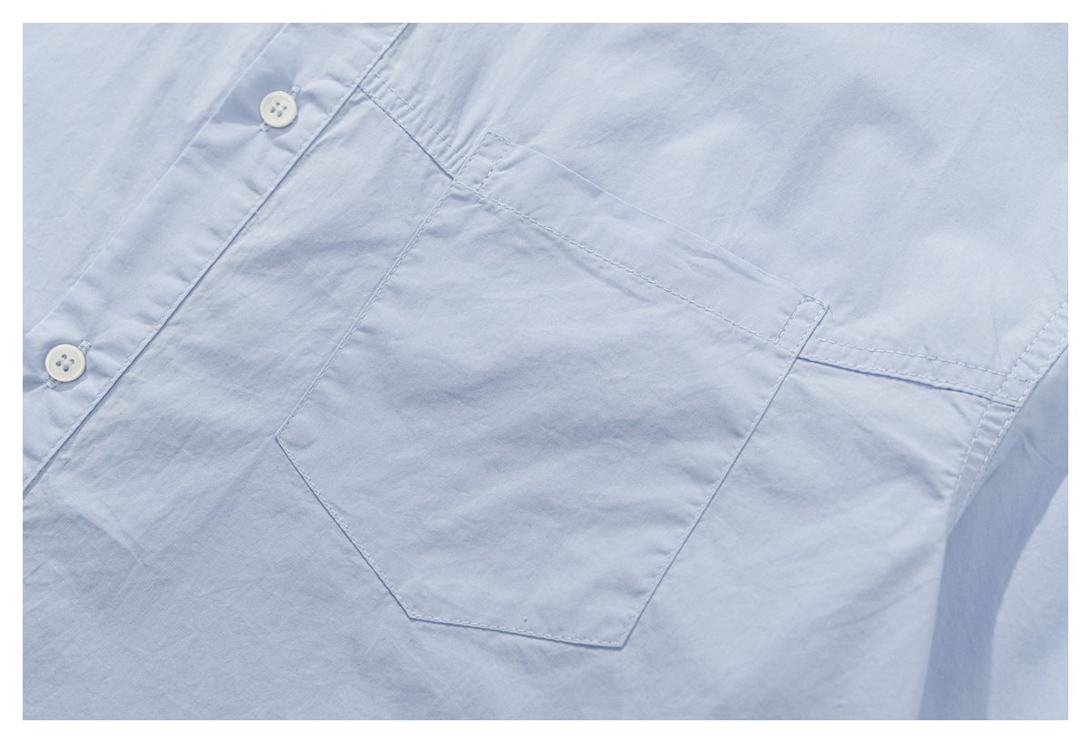 Close-up of the pale blue shirt's stitched chest pocket and white buttons.
