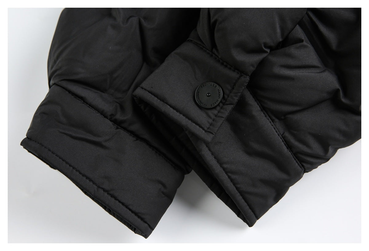 Close-up of a black padded jacket cuff with a button tab and round black button.