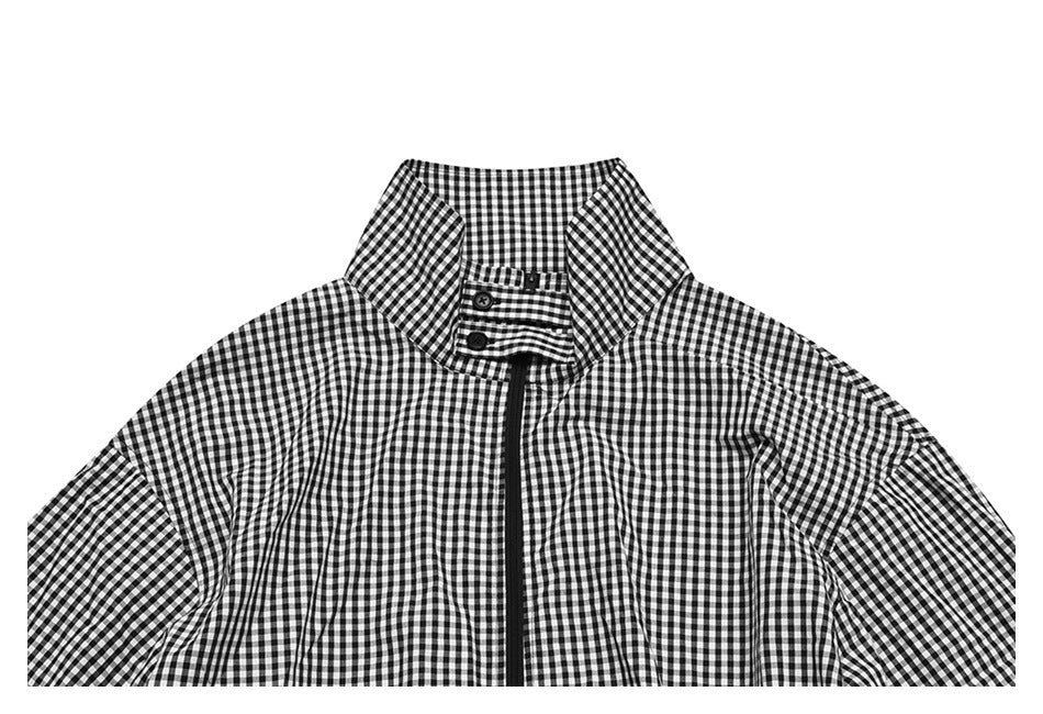 Cropped front view of a black-and-white gingham jacket, showing its tall collar, button tab and central zipper.