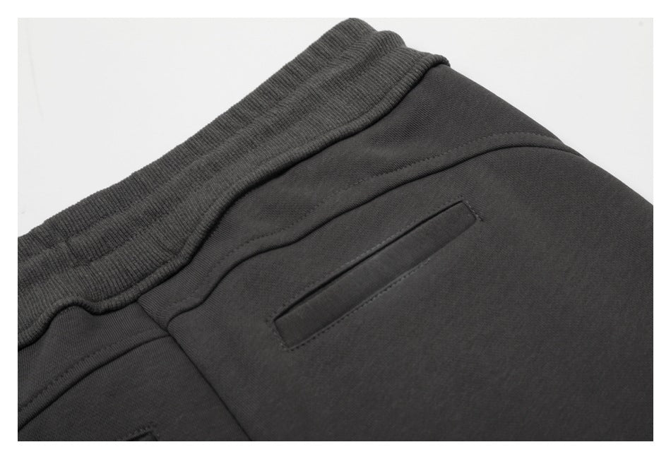 Close-up of the charcoal pants' elastic waistband and a welt pocket.