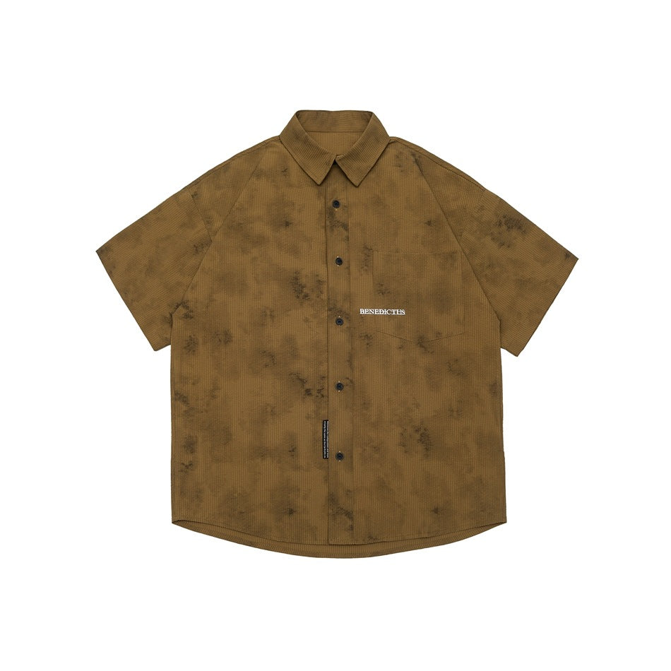 Khaki-brown short-sleeve button-up shirt with mottled dark distressed pattern and chest pocket, flat lay front view