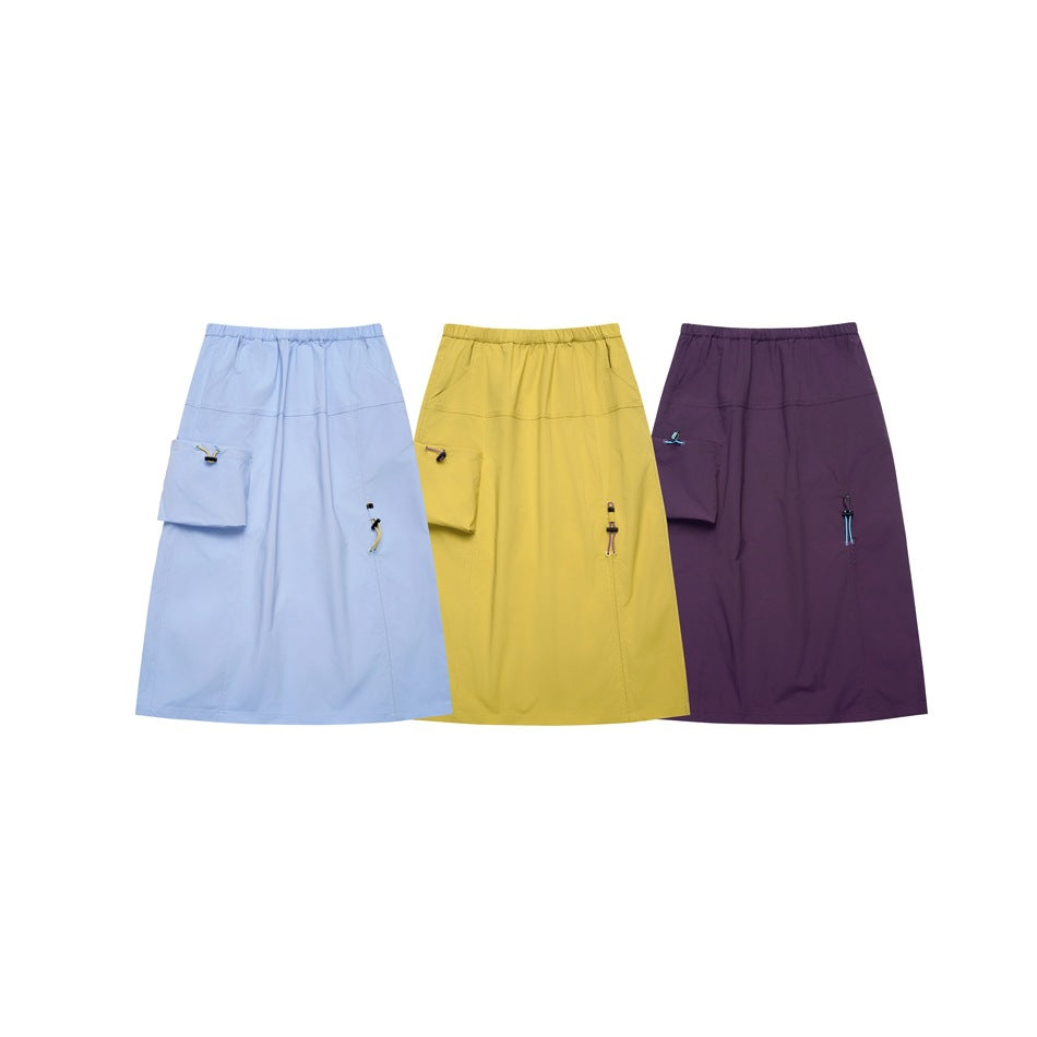 Three midi skirts shown together in light blue, yellow, and dark purple, each with a side pocket and drawcord detail.