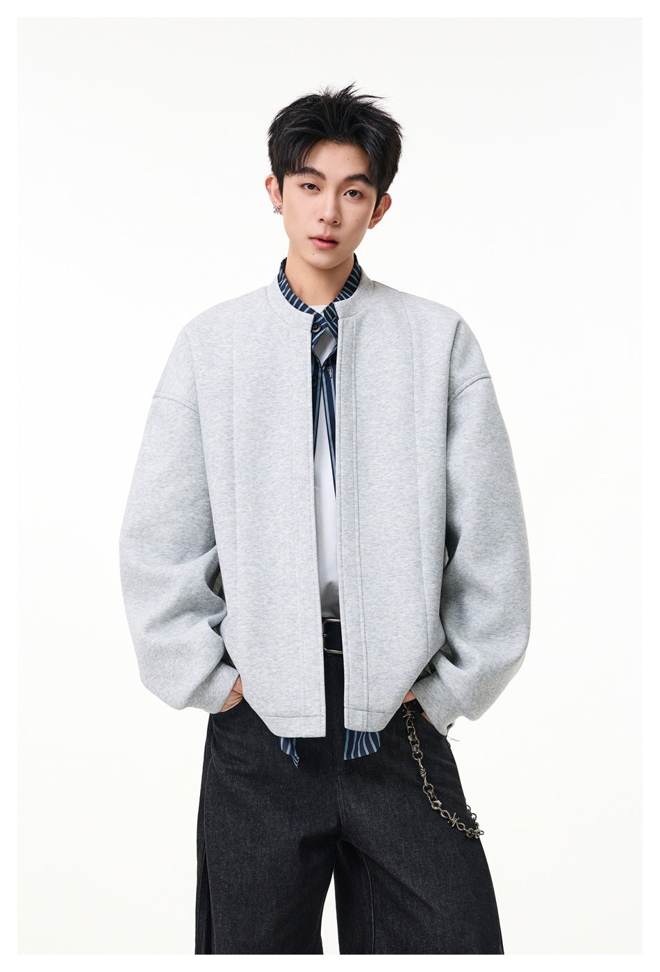 Front view of a model wearing a light gray jacket with striped trim and wide black trousers.
