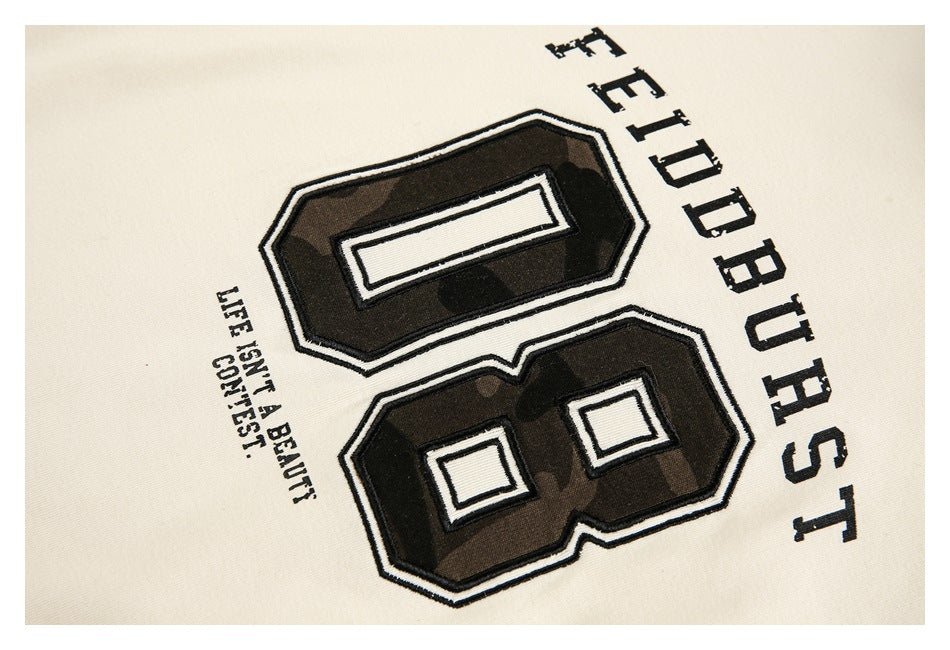 Close-up of the shirt's dark camouflage number graphic with outlined lettering on cream fabric.