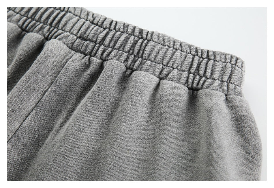 Close-up of the gathered, stitched elastic waistband on gray sweatpants.