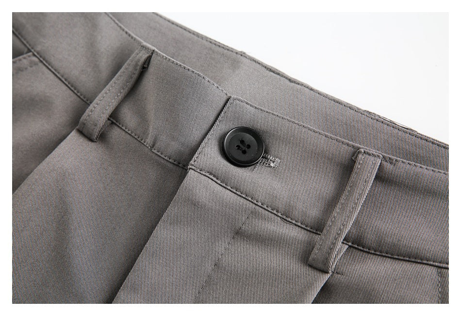 Close-up of gray trousers showing a black waistband button, belt loops, stitching, and fabric texture.
