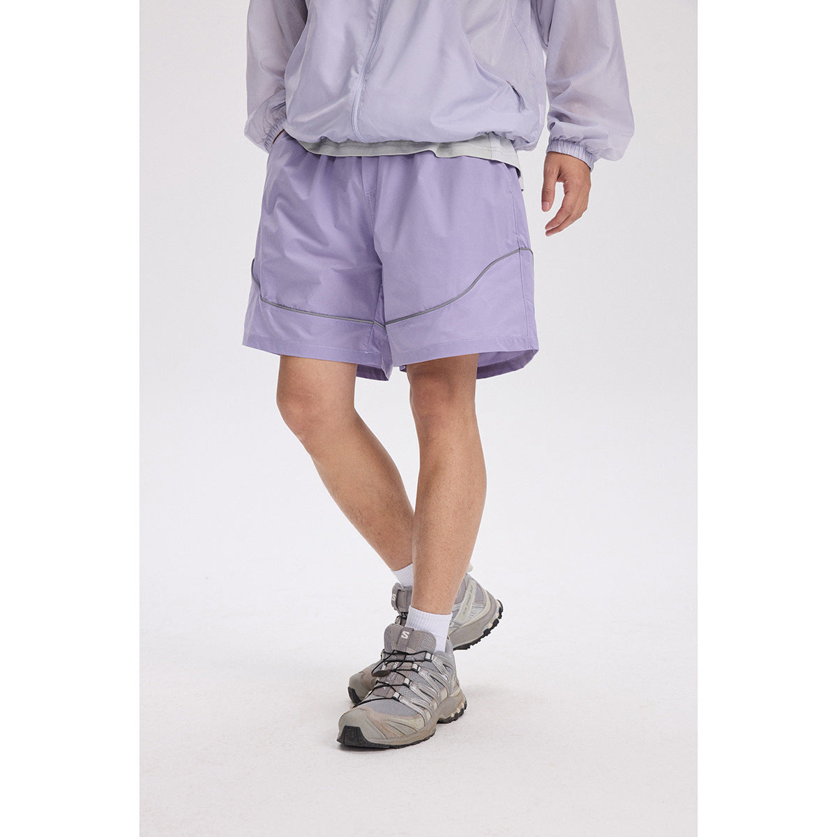 Cropped model wearing lavender athletic shorts with curved contrast piping and a matching zip jacket.