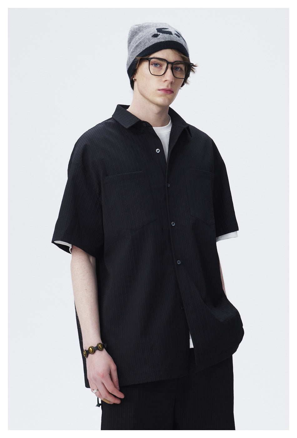 Closer view of a model wearing a black short-sleeve button-up shirt with two chest pockets.
