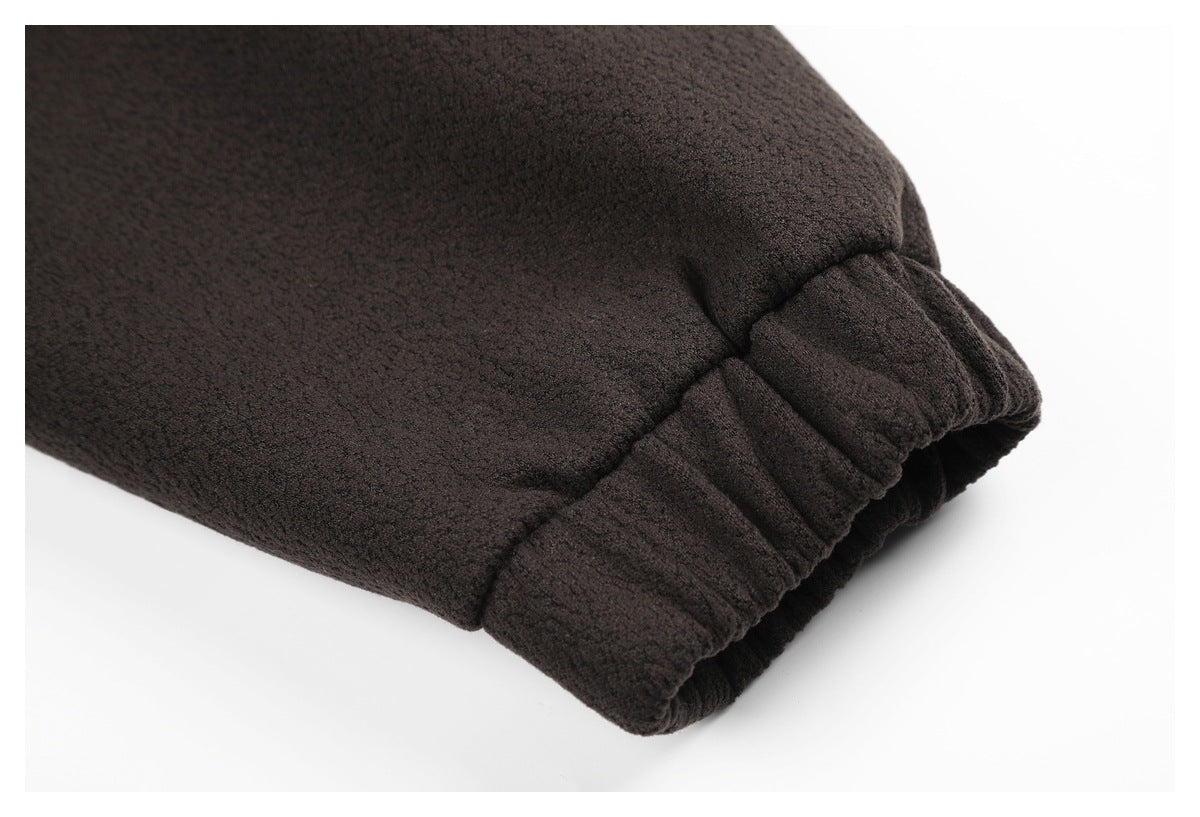 Close-up of a gathered cuff on a dark brown textured garment.