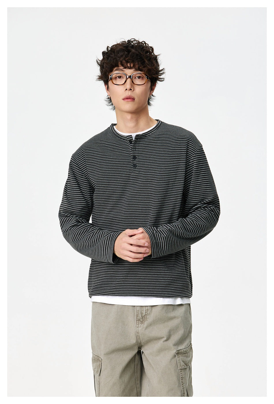 Model wearing the gray striped henley over a white tee with olive cargo pants, front view